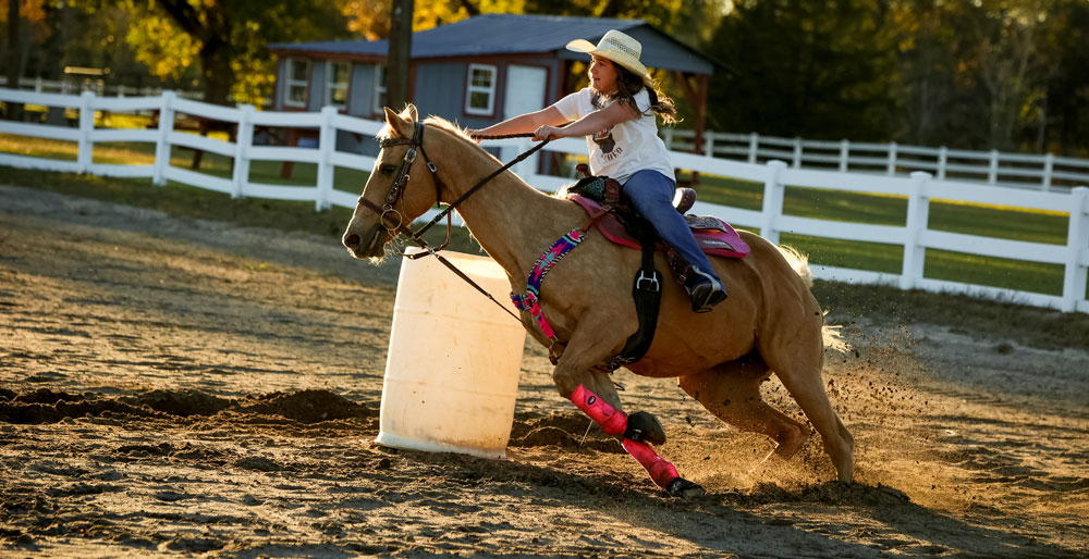 Ella Nipper is riding her palomino horse and turning a barrel. 